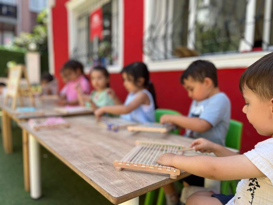 Bahçede dokuma etkinliği yapan çocuklar